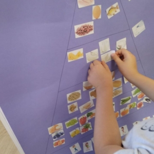 Na fioletowym papierze dzieci budują piramidę zdrowia, kulinarną przyklejając karteczki z produktami apożywczymi
